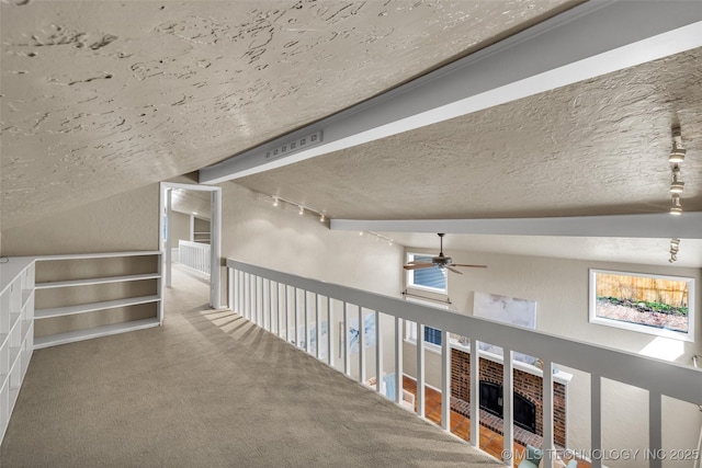 hallway with carpet floors, vaulted ceiling, a textured ceiling, and a textured wall