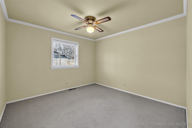 carpeted spare room with visible vents, crown molding, baseboards, and ceiling fan