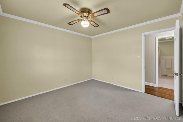 empty room featuring baseboards, ornamental molding, dark carpet, and a ceiling fan