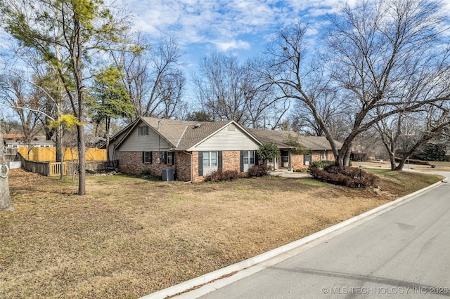 view of front facade featuring a front lawn, fence, and brick siding