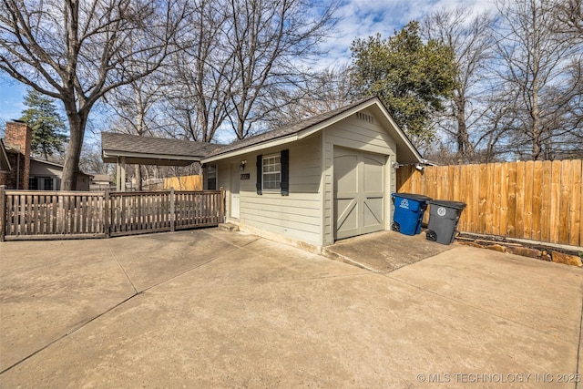 view of front facade featuring an outbuilding, a patio, concrete driveway, fence, and a garage