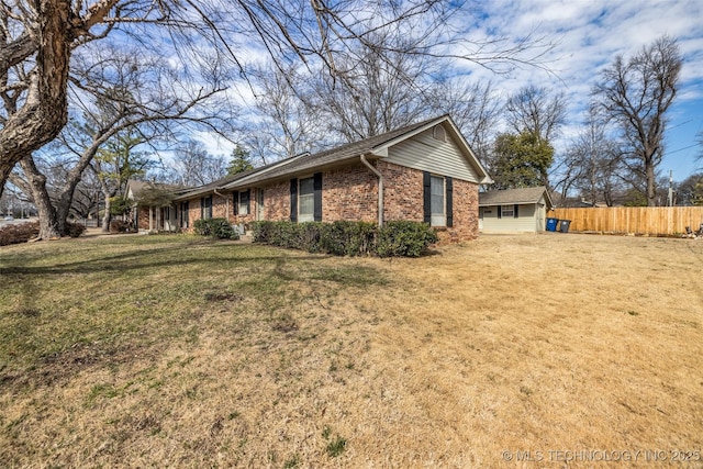 view of side of home with a yard, fence, and brick siding