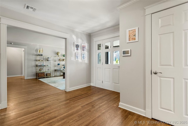 entrance foyer with ornamental molding, visible vents, baseboards, and wood finished floors