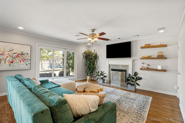 living room with ornamental molding, baseboards, a fireplace with flush hearth, and wood finished floors