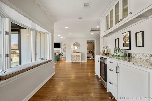 interior space featuring dark wood-style flooring, crown molding, visible vents, beverage cooler, and baseboards