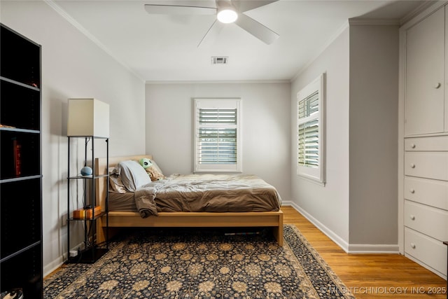 bedroom with light wood-style flooring, visible vents, baseboards, and ornamental molding