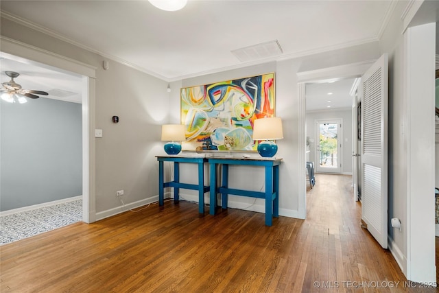 corridor featuring baseboards, visible vents, ornamental molding, and wood finished floors