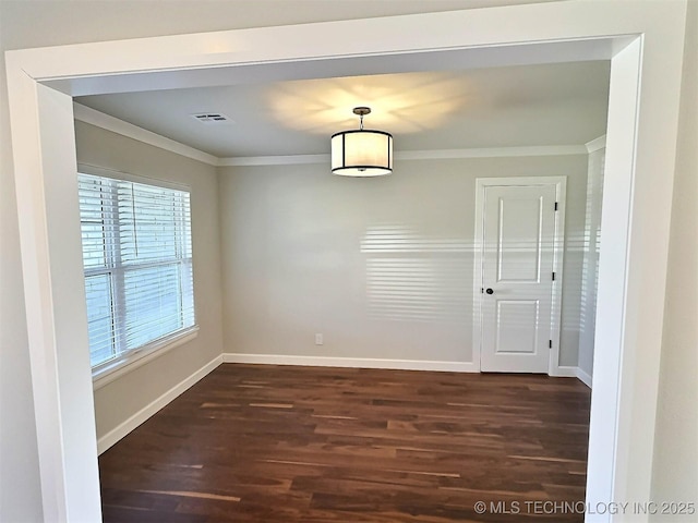 unfurnished dining area with dark wood finished floors, visible vents, crown molding, and baseboards