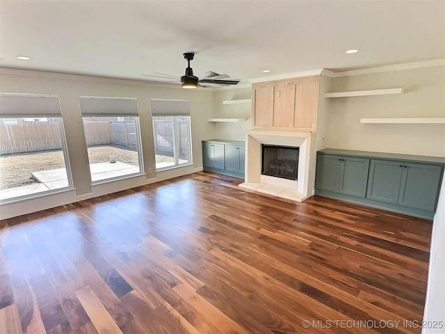 unfurnished living room with a fireplace with raised hearth, dark wood-style flooring, a ceiling fan, and recessed lighting