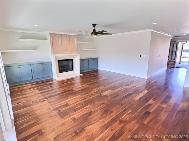 unfurnished living room featuring a large fireplace, wood finished floors, a ceiling fan, baseboards, and crown molding