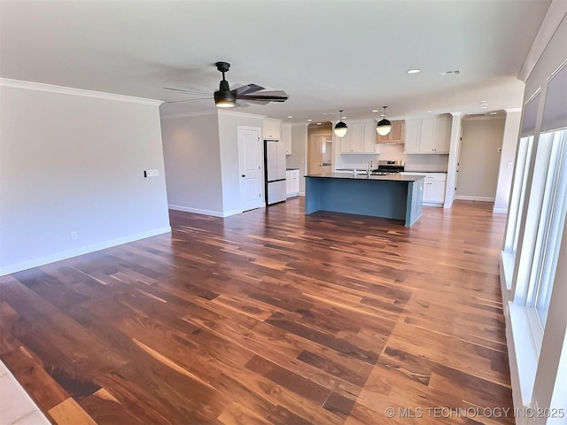 unfurnished living room with ornamental molding, visible vents, dark wood finished floors, and baseboards