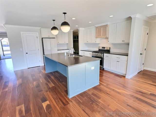 kitchen featuring dark countertops, gas stove, a sink, and freestanding refrigerator