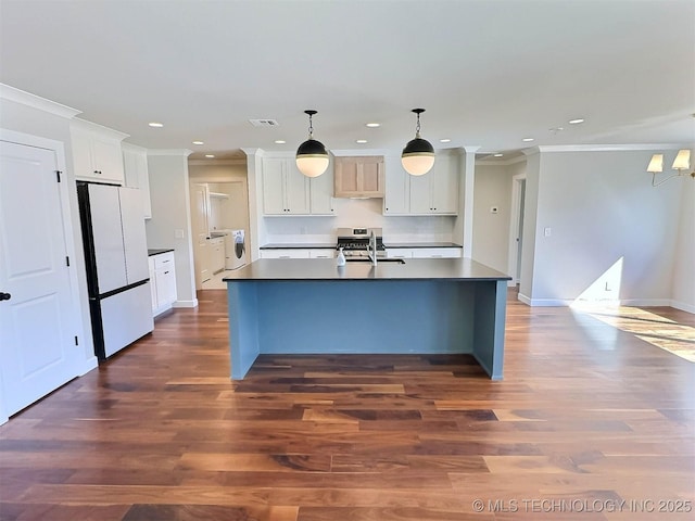 kitchen featuring dark wood-type flooring, freestanding refrigerator, crown molding, and dark countertops