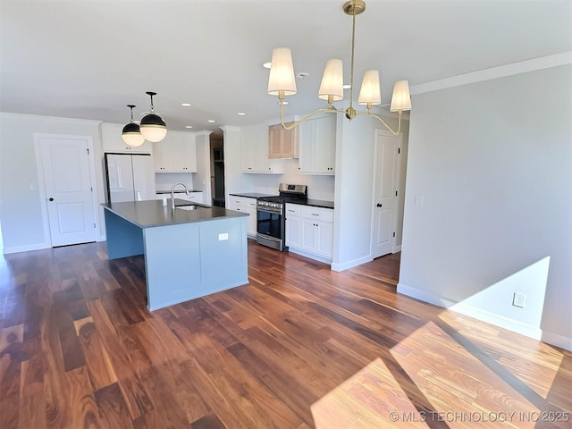 kitchen featuring dark countertops, dark wood-type flooring, freestanding refrigerator, stainless steel gas stove, and a sink