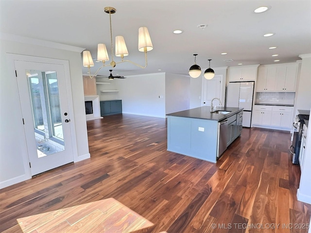 kitchen with stainless steel appliances, a sink, dark wood-style floors, dark countertops, and crown molding