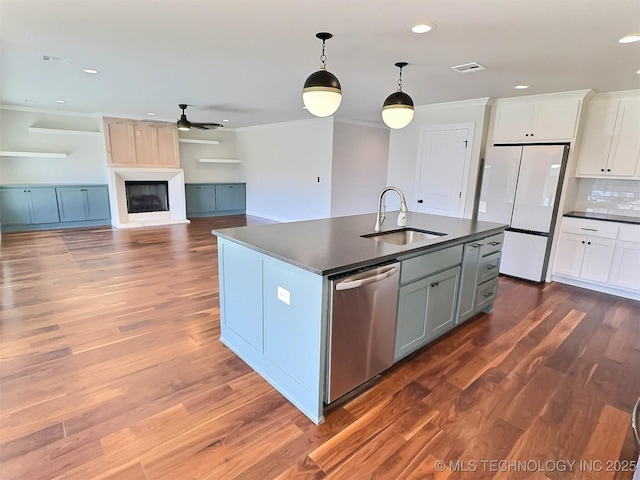 kitchen with dark countertops, a sink, dishwasher, and freestanding refrigerator