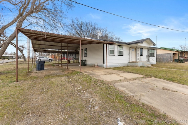 view of front of house featuring an attached carport, concrete driveway, metal roof, and a front lawn