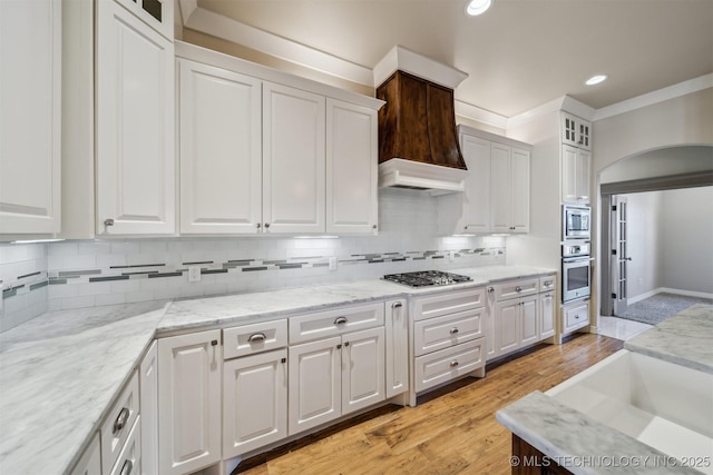 kitchen featuring arched walkways, recessed lighting, decorative backsplash, appliances with stainless steel finishes, and white cabinets