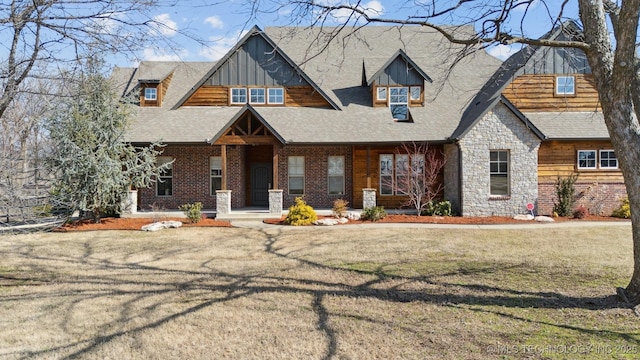 craftsman house with stone siding, roof with shingles, a front lawn, a porch, and brick siding