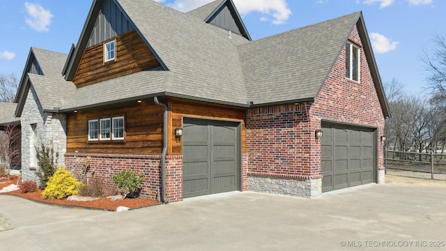 view of side of home with a garage, driveway, a shingled roof, and brick siding