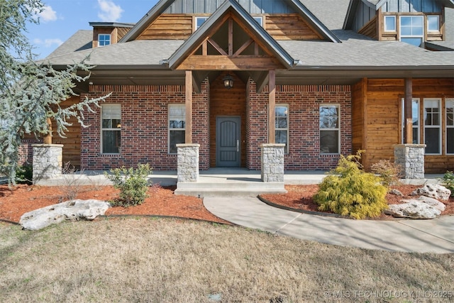 craftsman-style house with board and batten siding, covered porch, brick siding, and roof with shingles