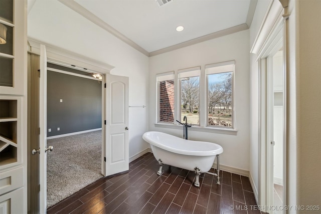 bathroom with visible vents, baseboards, a soaking tub, wood tiled floor, and crown molding