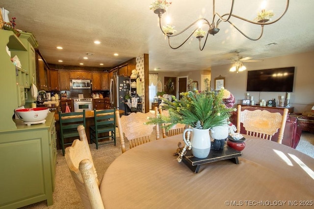 dining room with a textured ceiling, ceiling fan with notable chandelier, light colored carpet, and recessed lighting