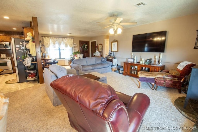 living area featuring a ceiling fan, visible vents, light carpet, and a textured ceiling