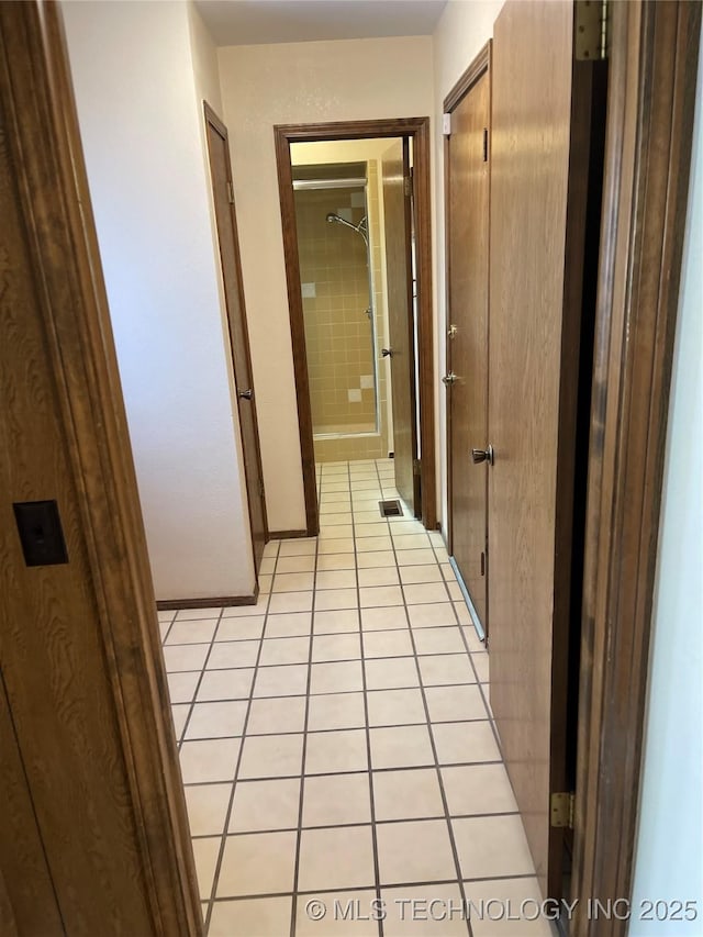 hall featuring visible vents, baseboards, and light tile patterned floors