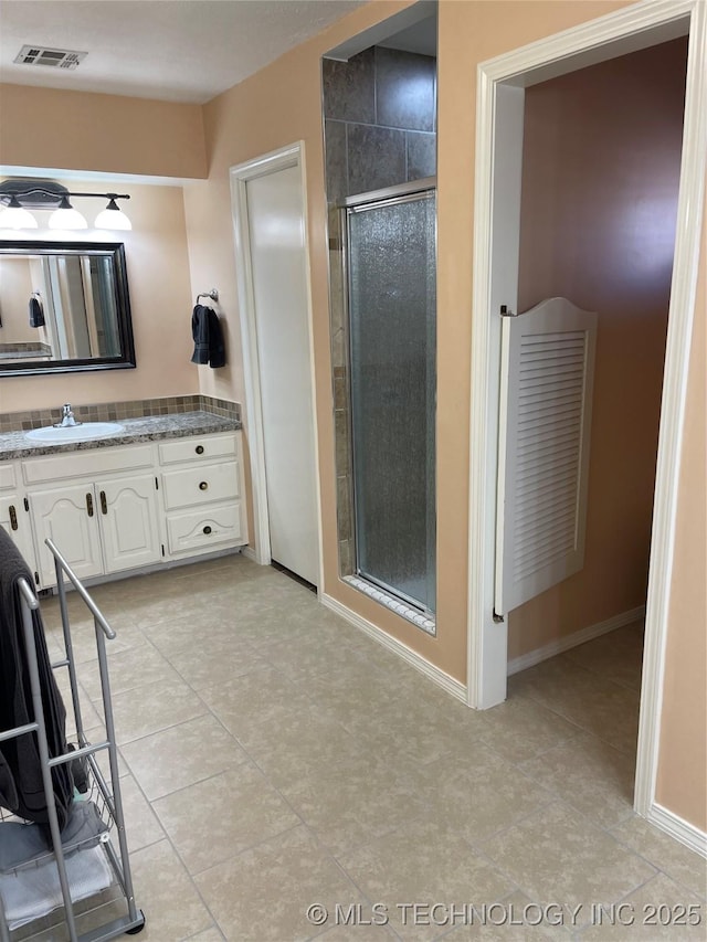 bathroom featuring vanity, visible vents, baseboards, a shower stall, and tile patterned floors