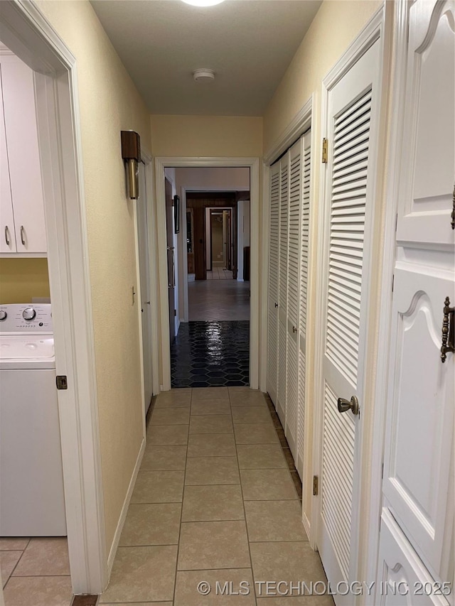 hallway featuring washer / dryer, baseboards, and light tile patterned floors