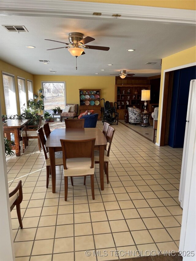 dining space with visible vents, a ceiling fan, and light tile patterned flooring