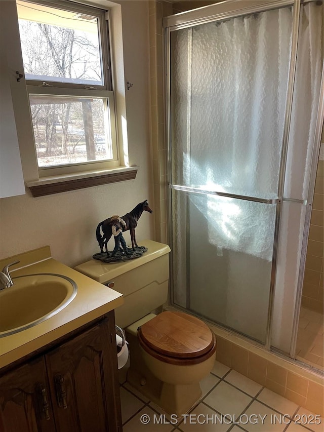 full bathroom with a stall shower, vanity, toilet, and tile patterned floors