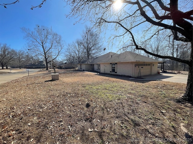 view of property exterior featuring a garage, concrete driveway, and brick siding