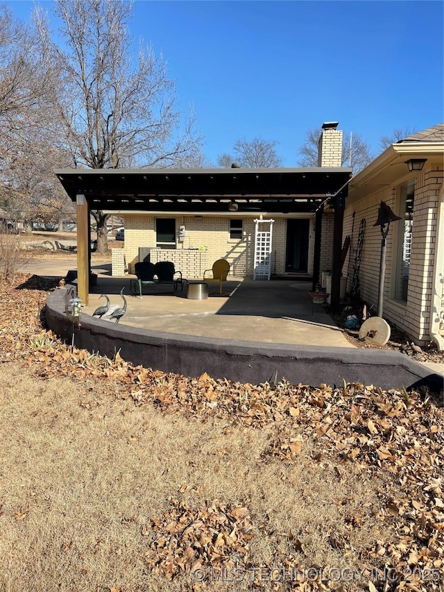 back of house with a patio area, a chimney, and brick siding