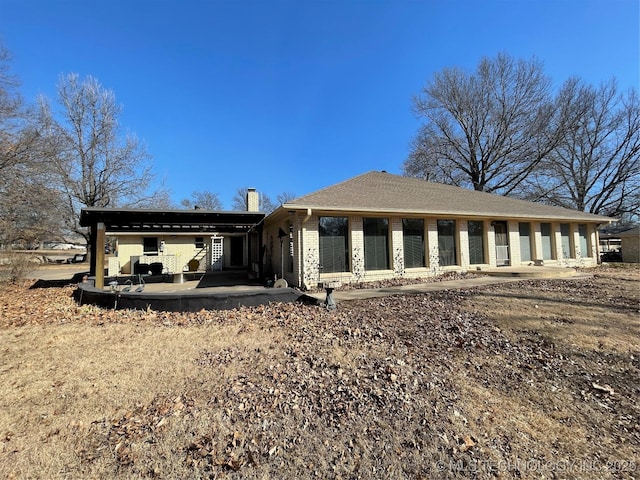 back of property with brick siding, a patio, a chimney, and roof with shingles