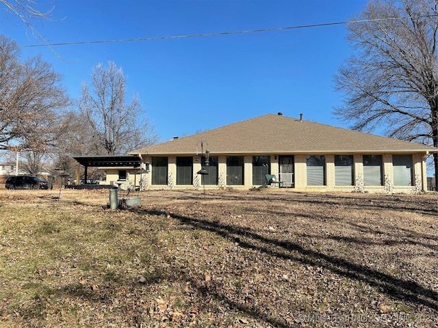 back of property with brick siding and roof with shingles