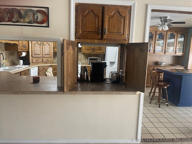 kitchen featuring dishwasher, a sink, decorative backsplash, and light tile patterned floors