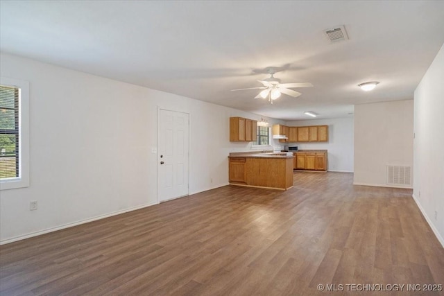 unfurnished living room with visible vents, ceiling fan, and wood finished floors