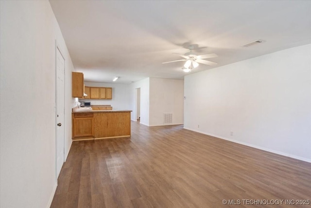 unfurnished living room with baseboards, dark wood finished floors, visible vents, and a ceiling fan