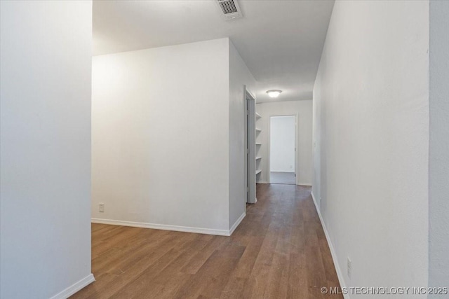 hallway featuring visible vents, baseboards, and wood finished floors