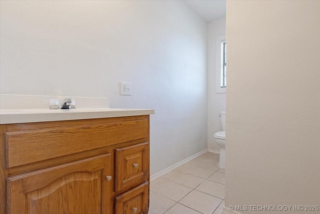 bathroom with tile patterned flooring, baseboards, vanity, and toilet