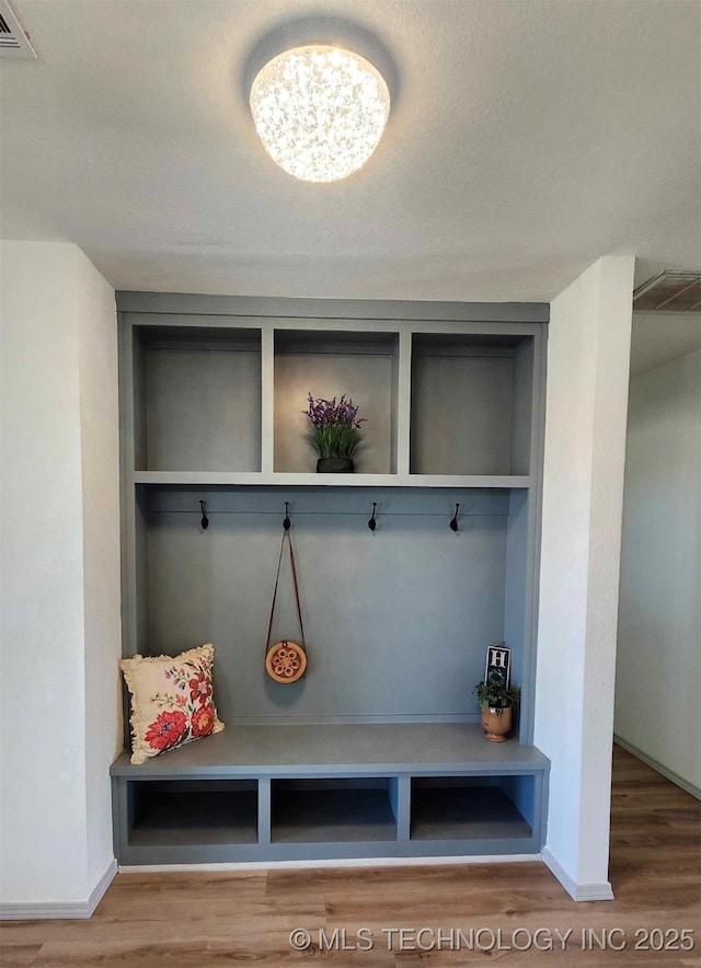 mudroom with built in features, baseboards, visible vents, and wood finished floors