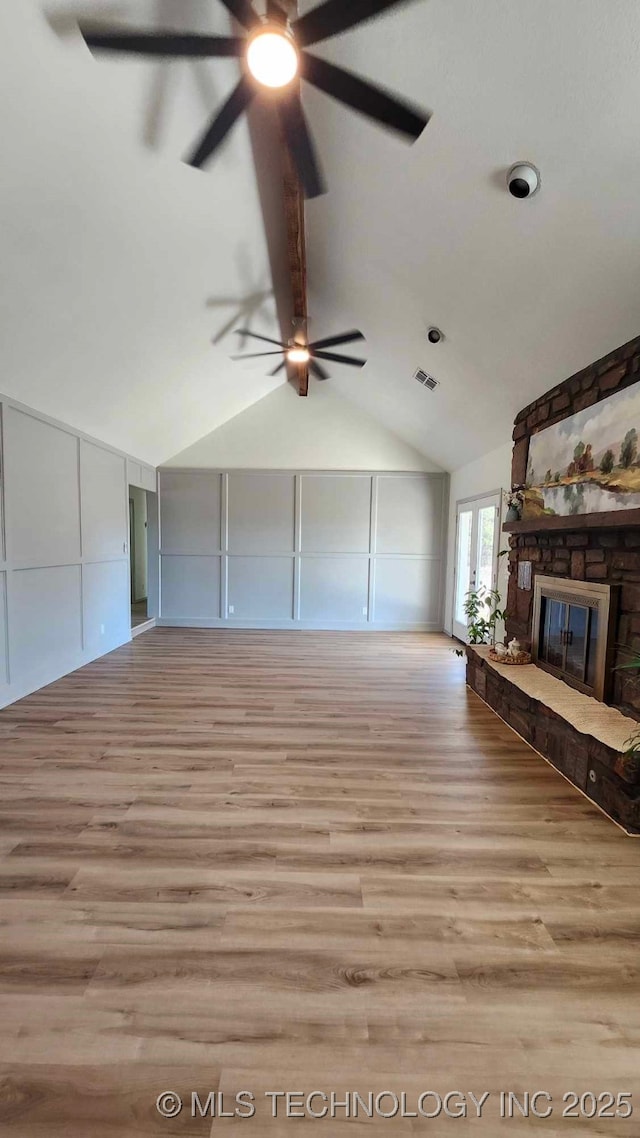 unfurnished living room featuring a fireplace, wood finished floors, visible vents, and a decorative wall