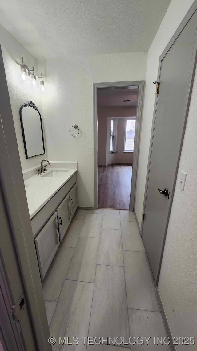 bathroom featuring a textured ceiling, baseboards, vanity, and tile patterned floors