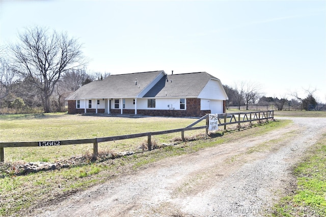 view of front of home with driveway, a fenced front yard, stone siding, a front yard, and a garage