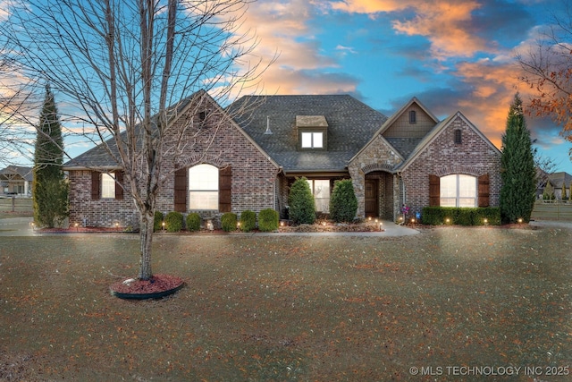 french country style house featuring stone siding and brick siding