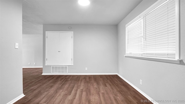 spare room featuring visible vents, baseboards, and wood finished floors