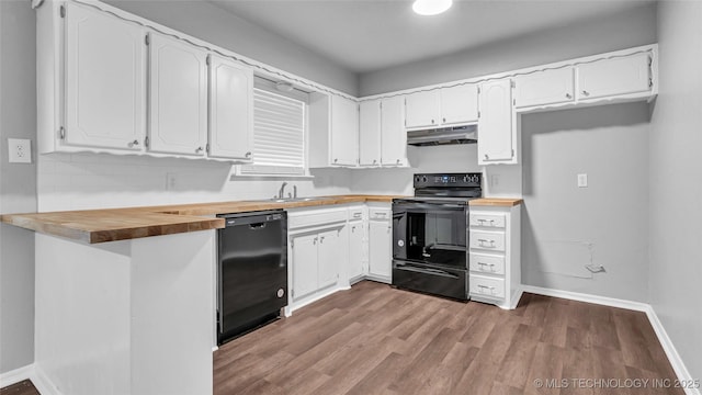 kitchen with butcher block countertops, wood finished floors, under cabinet range hood, black appliances, and white cabinetry