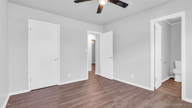 unfurnished bedroom featuring a ceiling fan, ensuite bath, baseboards, and wood finished floors